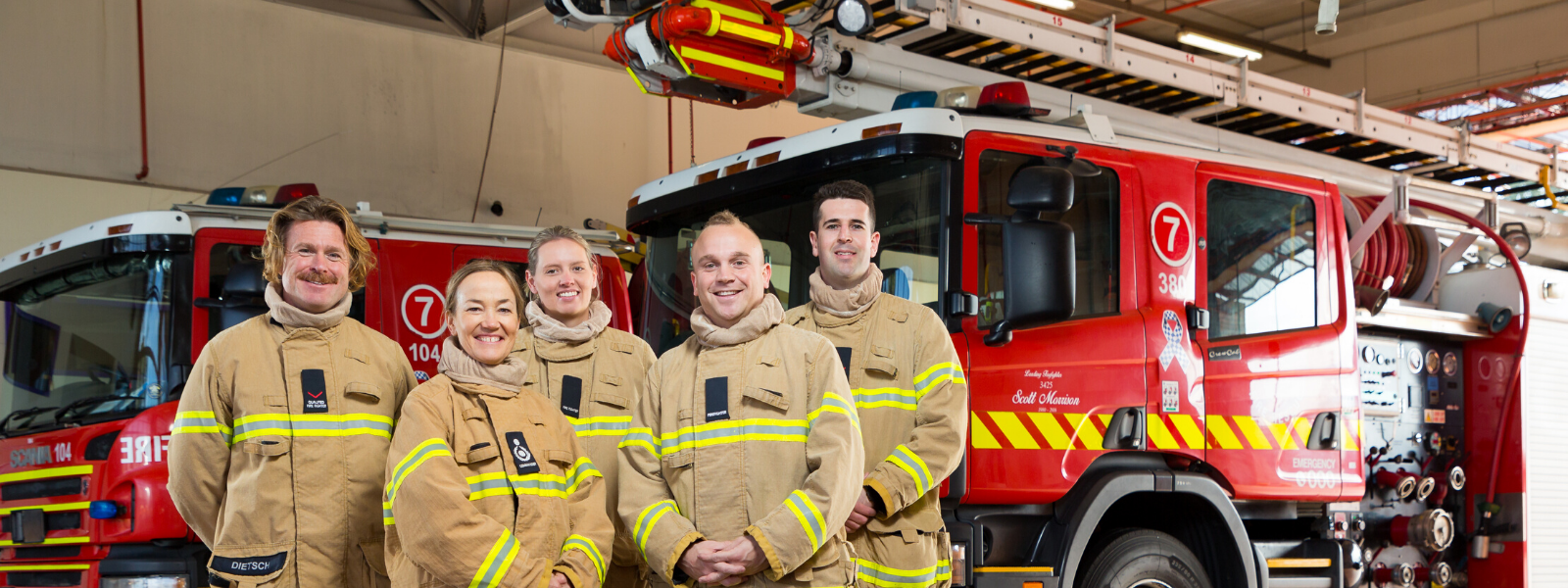 A group of five firefighters in front of a truck 